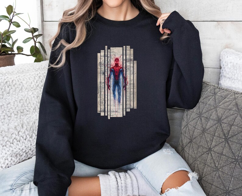 Op de afbeelding: Zwart sweatshirt met een Spiderman-afbeelding. De afbeelding toont Spiderman in een rood en blauw pak, tegen een vintage-achtige achtergrond met verticale lijnen. Het sweatshirt is effen zwart van kleur.