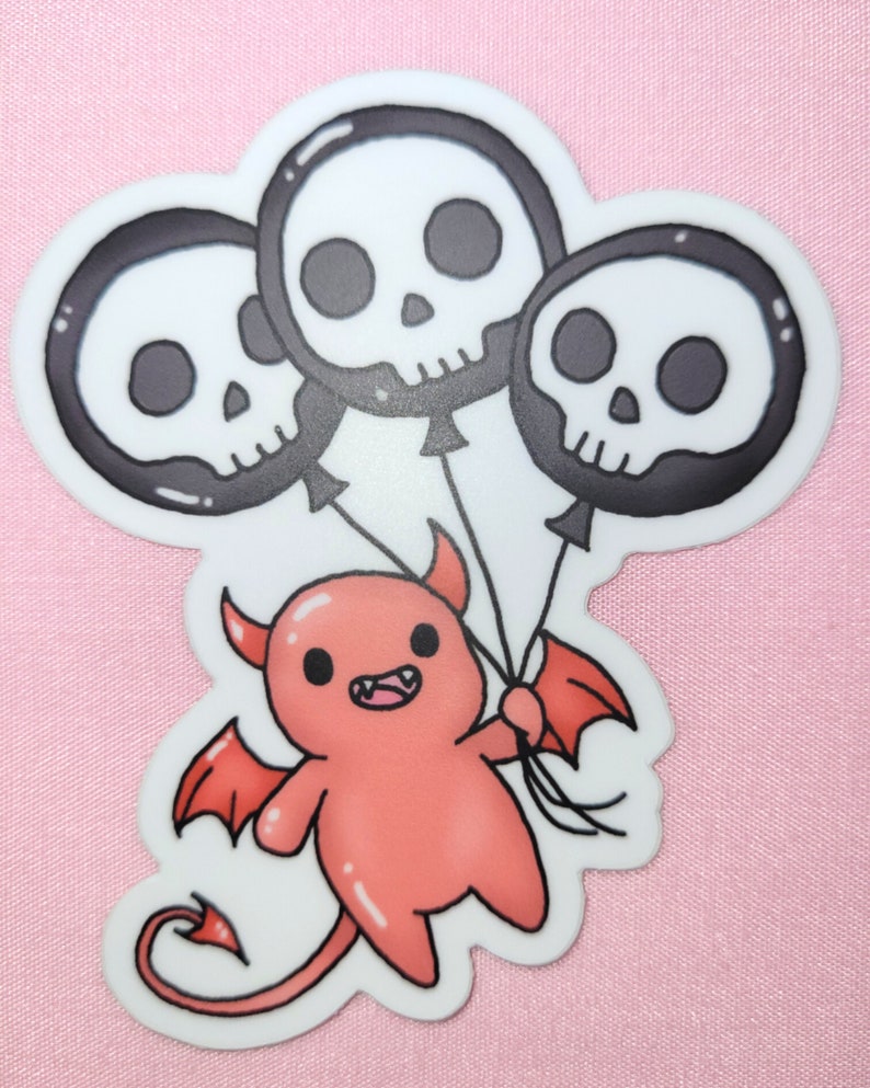 May include: A red cartoon devil with horns and wings holding three black and white skull balloons.