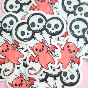 May include: A set of stickers featuring red cartoon devils holding black and white skull balloons. The stickers are on a pink background.