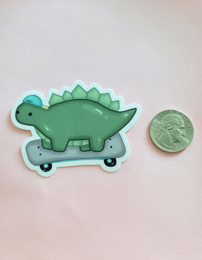 May include: A green dinosaur wearing a blue hat is skateboarding. The dinosaur has a spiky back and is on a grey skateboard with black wheels.