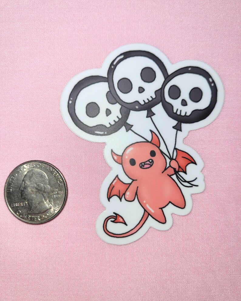 May include: A red cartoon devil with wings and a tail holds three black and white skull balloons. The balloons have black eyes and a white outline.