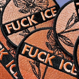 May include: Embroidered patches with the words "FUCK ICE" in orange lettering on a black banner. The patches are circular with a peach-colored background and black floral and leaf designs.