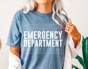 May include: A blue t-shirt with the text "EMERGENCY DEPARTMENT" printed in white, stacked and offset to create a visual effect. The shirt is being worn by a person with blonde hair.