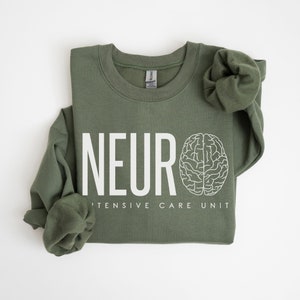 Puede incluir: Una sudadera verde con el texto "NEURO INTENSIVE CARE UNIT" y un contorno blanco de un cerebro.