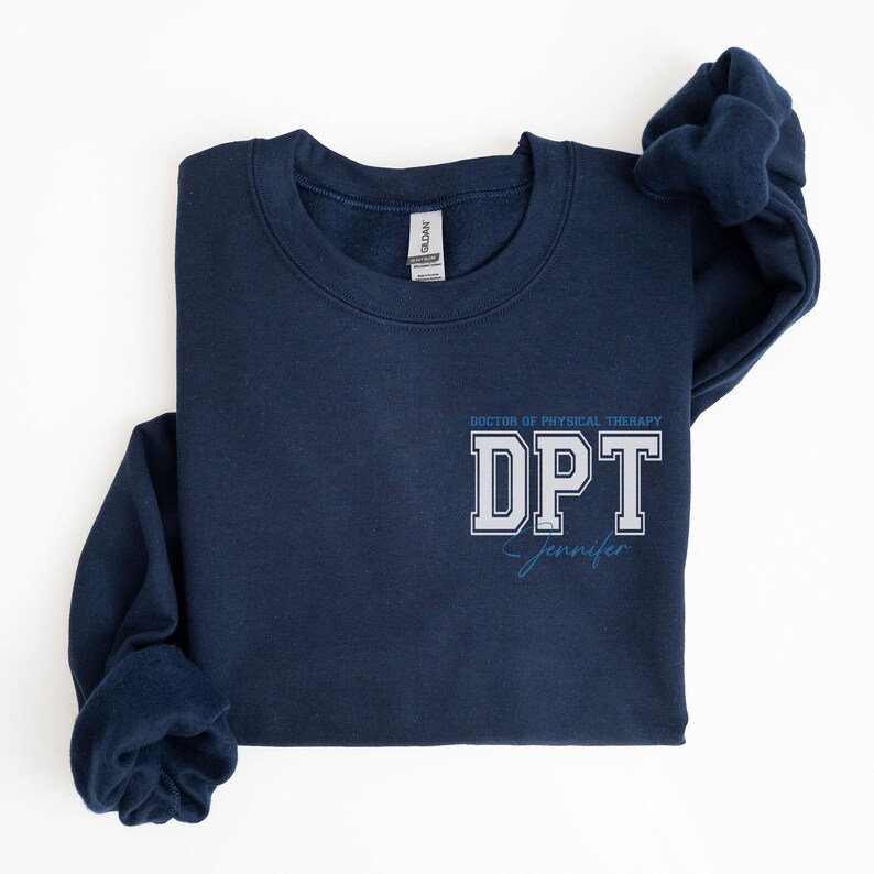Puede incluir: Una sudadera azul marino con el texto "Doctor of Physical Therapy DPT Jennifer" impreso en la parte delantera.