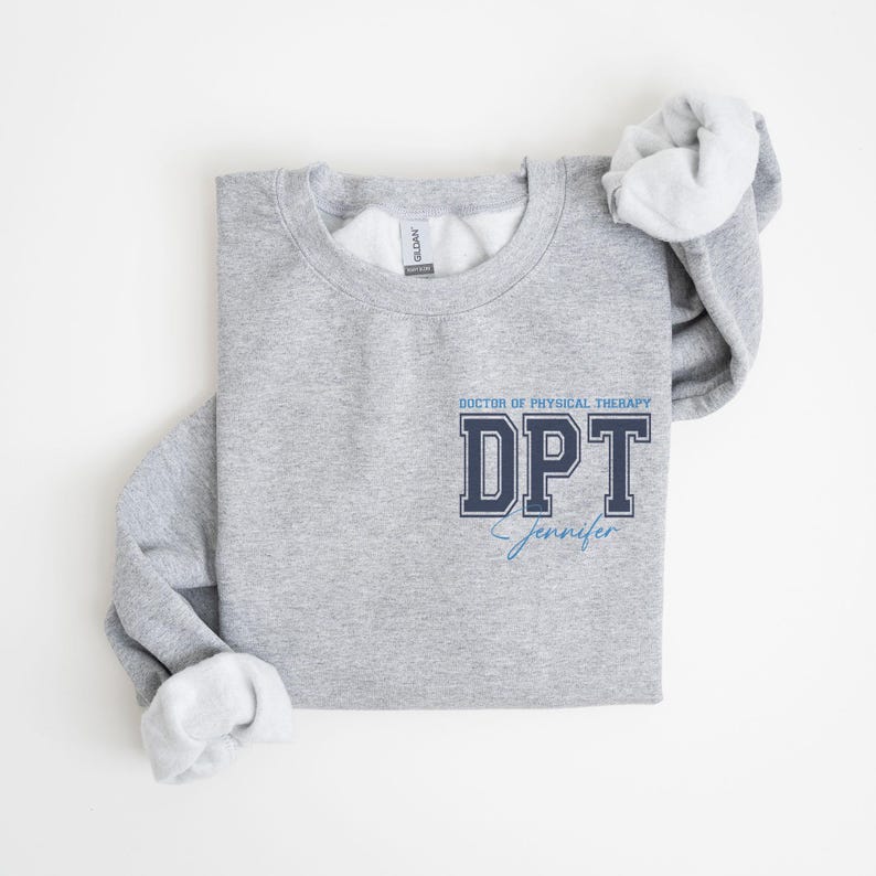 Puede incluir: Sudadera gris con el texto "DOCTOR OF PHYSICAL THERAPY DPT Jennifer" en letras azules y negras.