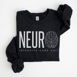 Puede incluir: Sudadera negra con texto blanco que dice "NEURO INTENSIVE CARE UNIT" y un contorno blanco de un cerebro.
