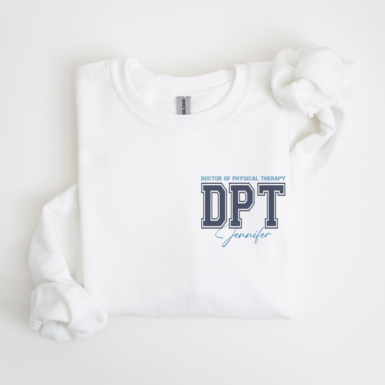 Puede incluir: Sudadera blanca con un gr&aacute;fico azul marino y blanco que dice "DOCTOR OF PHYSICAL THERAPY DPT Jennifer".