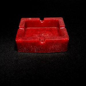 May include: A red square ashtray with a speckled finish.