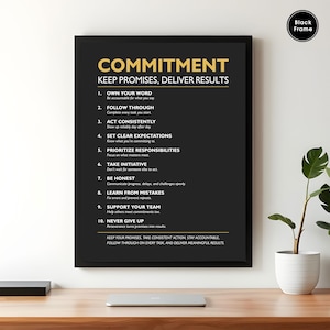 May include: Black framed poster with the word "COMMITMENT" in gold lettering. The poster lists ten principles for keeping promises and delivering results. The poster is on a wooden desk with a laptop and a potted plant.