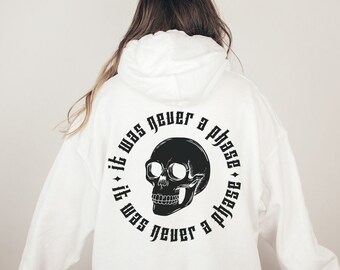 May include: White hoodie with a black skull graphic and the text "it was never a phase + it was never a phase" on the back.