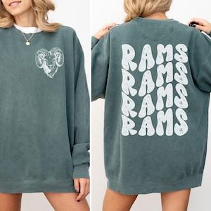 May include: A teal blue sweatshirt with a white ram graphic on the front and the word "RAMS" repeated five times in a retro font on the back.