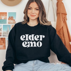 May include: Black sweatshirt with white text that reads "elder emo" in a retro font.