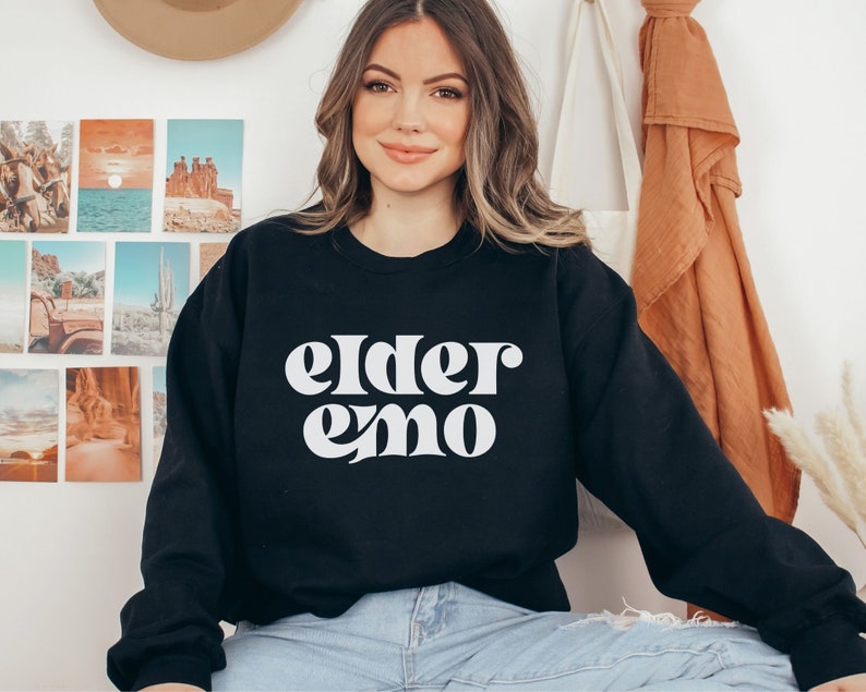 May include: Black sweatshirt with white text that reads "elder emo" in a retro font.