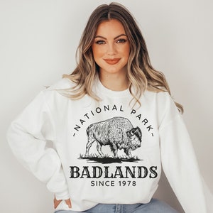 May include: White sweatshirt with a black graphic of a bison and the text "Badlands National Park - Since 1978"