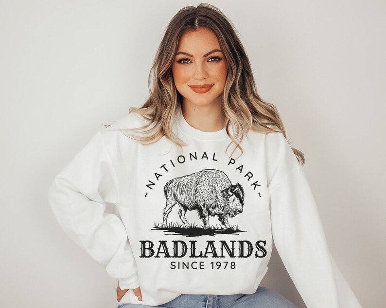 May include: White sweatshirt with a black graphic of a bison and the text "Badlands National Park - Since 1978"