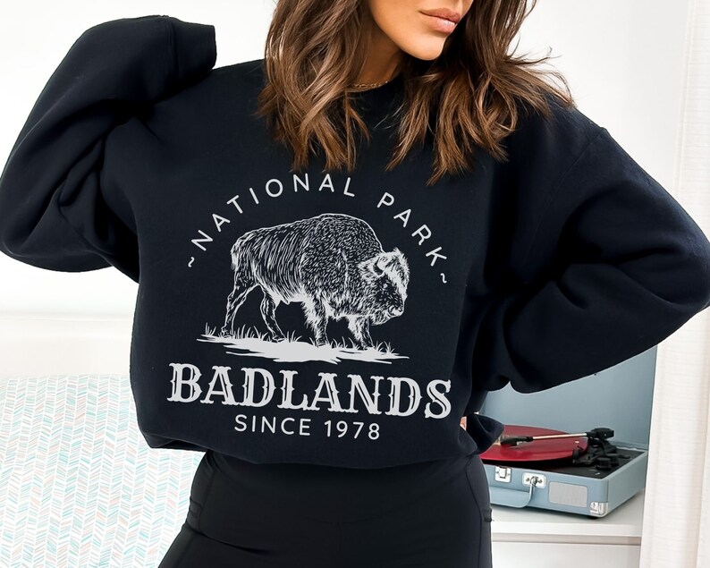 May include: Black sweatshirt with a white graphic of a buffalo and the text "National Park" and "Badlands Since 1978".