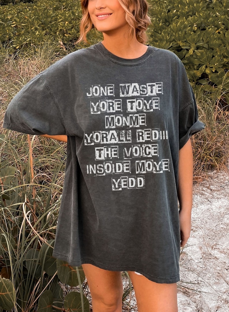 May include: A dark gray t-shirt with a white graphic print of the words "Jone Waste", "Yore Toye", "Monme", "Yore All Red", "The Voice", "Insoide Moye", and "Yedd".
