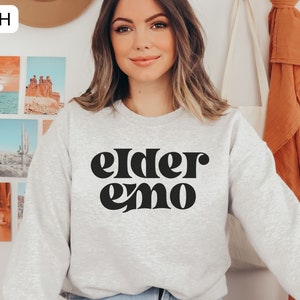 May include: A grey sweatshirt with the text "elder emo" printed in black retro-style lettering.