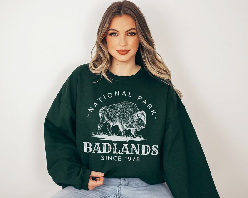 May include: A dark green sweatshirt with a white graphic of a bison and the text "National Park" and "Badlands Since 1978".