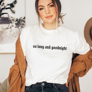 May include: White t-shirt with the text "so long and goodnight" printed in black.