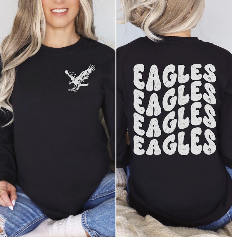 Peut inclure: T-shirt &agrave; manches longues noire avec un graphique d'aigle blanc sur le devant et le mot "EAGLES" r&eacute;p&eacute;t&eacute; dans une police r&eacute;tro au dos.