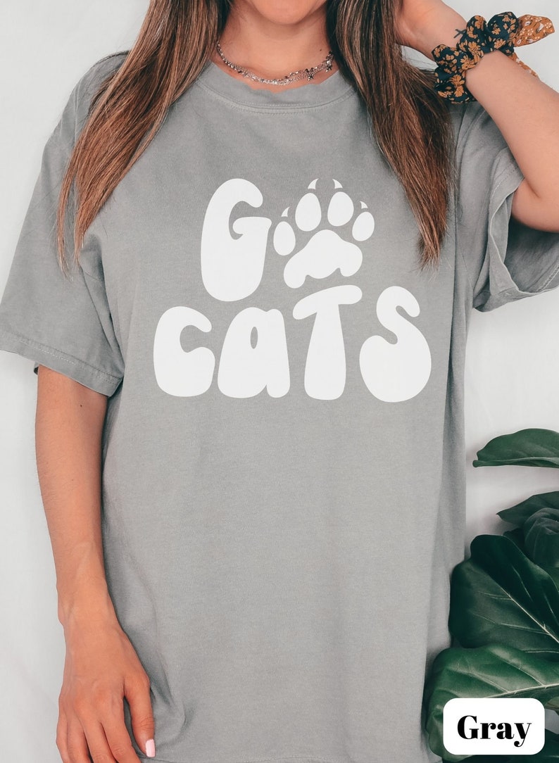 May include: Gray t-shirt with a white paw print and the text "Go Cats" in a retro font.