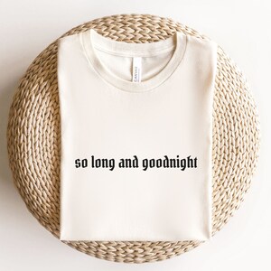May include: A cream-colored t-shirt with the text "so long and goodnight" printed in black.