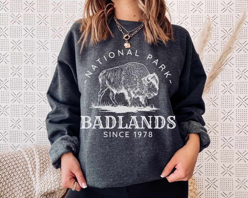 May include: A dark gray sweatshirt with a white graphic of a buffalo and the text "National Park - Badlands - Since 1978".