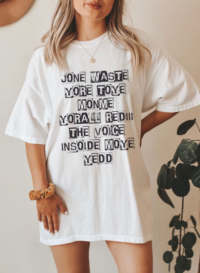 May include: White oversized t-shirt with black text that reads "Jone Waste Yore Toye Monme Yore All Red!! The Voice Insode Moye Yedd"