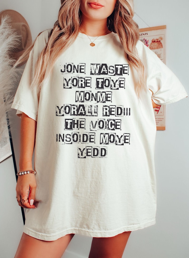 May include: White t-shirt with black text that reads "Jone Waste Yore Toye Monme Yore All Red!! The Voice Inside Moye Yedd"