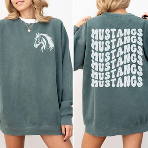 May include: A teal blue sweatshirt with a white horse silhouette on the front and the word "MUSTANGS" repeated six times in a retro font on the back.