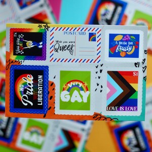Puede incluir: Un sobre blanco con pegatinas coloridas con diseños de arcoíris y frases como "No Pride Without Liberation", "Wish you were Queer", "Very Gay", "A little bit fruity" y "Love is Love".