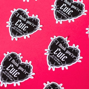 Puede incluir: Cinco pegatinas en forma de corazón en blanco y negro con alambre de púas alrededor de los bordes. Las pegatinas dicen "Creo que eres lindo" y "sí, estoy usando una pegatina para ligar contigo".