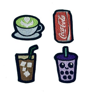 Może przedstawiać: Haftowane naszywki przedstawiające napoje: matcha latte, puszkę Coca-Coli, mrożoną kawę i fioletową herbatę bąbelkową z uśmiechniętą buzią. Każda naszywka ma czarną obwódkę i jest przeznaczona do nakładania na tkaninę.