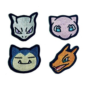以下が含まれることがあります： 人気の漫画のキャラクターが描かれた4つの刺繍パッチ。パッチには、紫色の目を持つ灰色の猫のような生き物、青い目を持つピンク色の猫のような生き物、ニュートラルな表情の青い猫のような生き物、オレンジ色のドラゴンに似た生き物が含まれています。