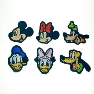 May include: Six embroidered patches featuring cartoon characters. Includes Mickey Mouse, Minnie Mouse, Goofy, Donald Duck, Daisy Duck, and Pluto. Each patch has a black border and bright colours, ideal for decorating clothing or accessories.