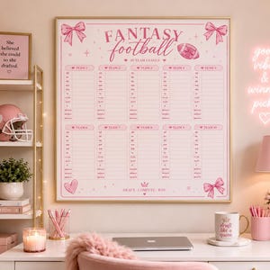 May include: A large rectangular wall poster with a pink and white fantasy football draft board featuring ten team columns, bows, a football, and the text "FANTASY football" and "DRAFT. COMPETE. WIN." The board is framed in gold and displayed on a wall.