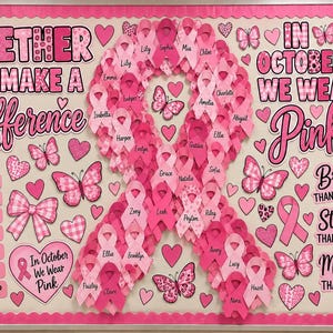 Puede incluir: Un tablón de anuncios con un gran lazo de concienciación central compuesto por lazos rosas más pequeños, cada uno con un nombre. El tablero incluye el texto Together We Make A Difference, In October We Wear Pink y varias frases inspiradoras.