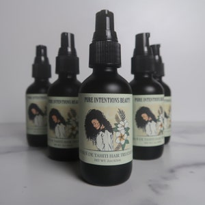 May include: Several black bottles of hair treatment are arranged on a white surface. Each bottle has a black pump and a label with the text "PURE INTENTIONS BEAUTY" and "MONOI DE TAHITI HAIR TREATMENT". The label also features an illustration of a woman and flowers. Each bottle contains 2oz/60ml.