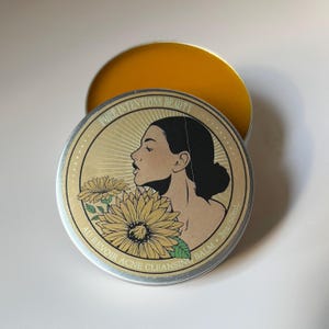 Pu&ograve; includere: Un barattolo rotondo d'argento di balsamo detergente per l'acne con interno dorato. Il coperchio presenta il profilo di una donna, girasoli e il testo "PURE INTENTIONS BEAUTY" e "AU REVOIR ACNE CLEANSING BALM". Il balsamo &egrave; di 60 ml.