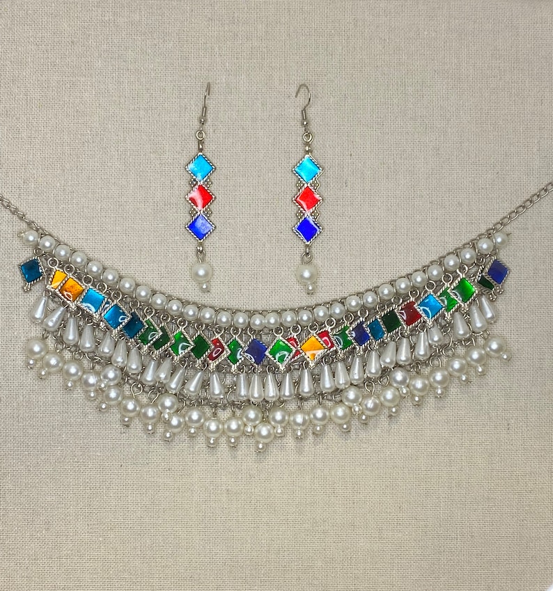 Peut inclure: Un collier en argent avec un motif de carreaux de verre multicolores et des accents de perles. Le collier est assorti &agrave; des boucles d'oreilles.