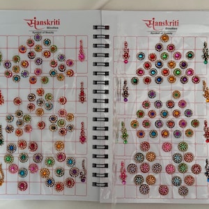 May include: Two-page spread of bindis in a spiral-bound book. The bindis are arranged in a grid pattern and come in various colors, including red, green, blue, and gold. The brand name "Sanskriti Bindies" is printed at the top of each page.