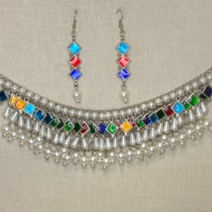 Peut inclure: Un collier en argent avec un motif en &eacute;mail multicolore et des accents de perles blanches. Le collier a un design en couches avec plusieurs rang&eacute;es de perles. Des boucles d'oreilles assorties avec un design en &eacute;mail similaire sont incluses.
