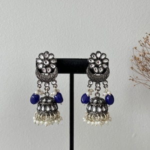 May include: Silver tone earrings with a floral design, blue beads, and white pearl accents.