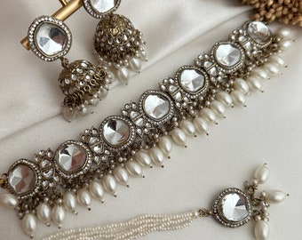 May include: A silver and white necklace with large, clear, faceted stones and pearl accents. The necklace is paired with matching earrings with a similar design.