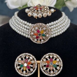 This choker has off- white pearls, stone and Kundan work on studs, central piece and tikka.
