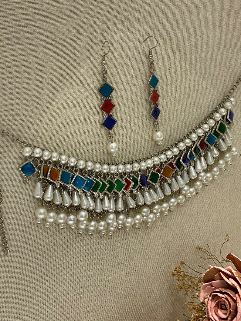 Peut inclure: Un collier en argent avec une rang&eacute;e de carreaux carr&eacute;s color&eacute;s et une frange de perles blanches. Boucles d'oreilles assorties avec trois carreaux carr&eacute;s color&eacute;s et une seule perle pendante.
