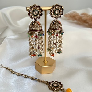 May include: A pair of gold earrings with a floral design and pearl and colourful bead drops. A matching gold nose ring with a floral design and a yellow bead.