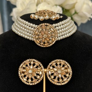 this choker has off-white pearls and paired with gold stonework on earrings, centrepiece and tikka